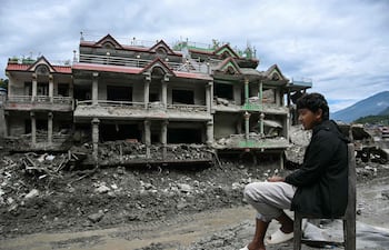 Un hombre descansa sentado frente a un edificio dañado por la riada en Nuwakot, Nepal.