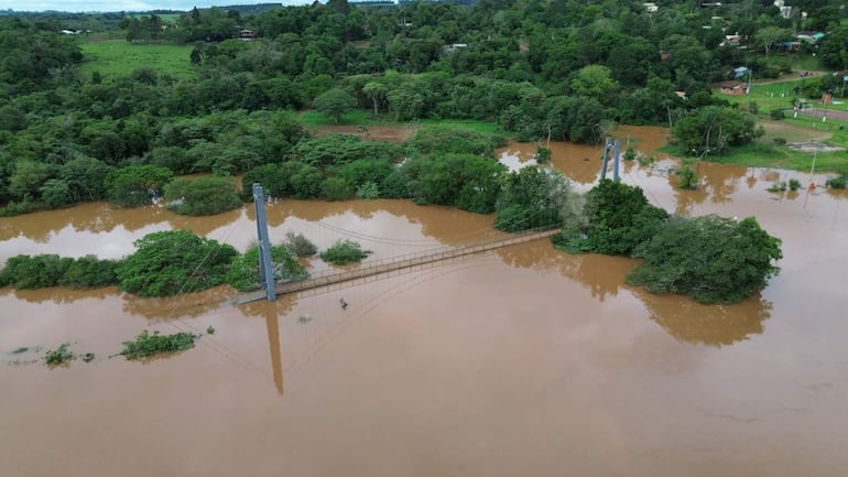 Paisaje inundado en Puerto Capitán Meza con el Puente Colgante parcialmente sumergido y vegetación rodeante.