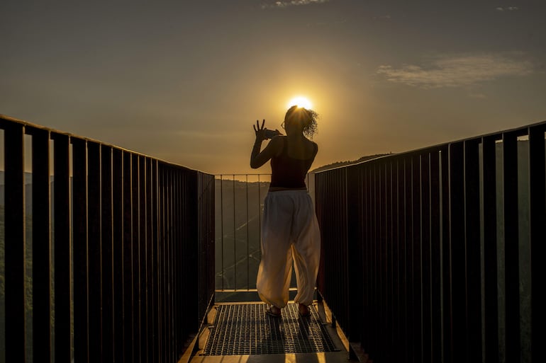 Una mujer toma fotografías del atardecer y del cañón del río Sil desde el Mirador de Matacás, en Castro Caldelas (Ourense), este martes, un día antes del eclipse solar.