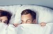 Imagen ilustrativa de una pareja heterosexual cubierta en una cama cubiertos con una sábana.
