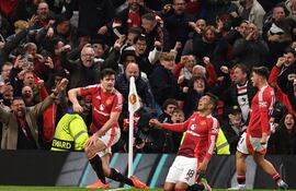Manchester United's English defender #05 Harry Maguire (L) and teammates celebrate with their fans after Maguire scores their fifth goal during the UEFA Europa league quarter-final final, second leg football match between Manchester United and Lyon at Old Trafford stadium in Manchester, north west England, on April 17, 2025. (Photo by Oli SCARFF / AFP)