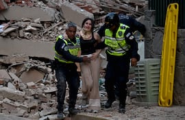 Policías ayudan a una mujer a evacuar tras el colapso de un edificio en Caracas a consecuencia de los seísmos de ayer.