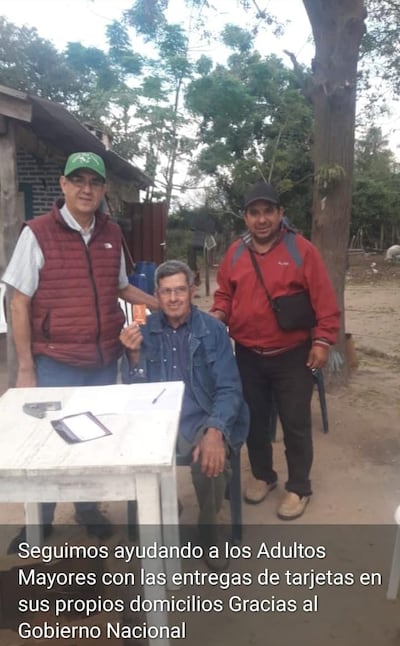 Héctor Cáceres, (Chaleco granate y quepis verde) candidato de la ANR a la Intendencia de Humaitá, posa junto a un adulto mayor y un candidato a Concejal durante la entrega de tarjetas para el cobro de la pensión destinada a personas mayores.