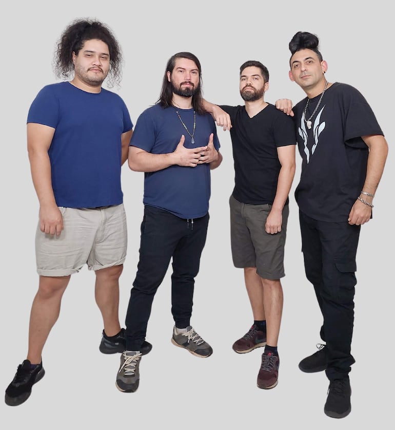 Cuatro hombres del grupo Tercer Piso, con camisetas de diferentes colores, posan de pie en un fondo gris, luciendo tranquilos.