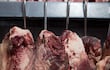 Cortes de carne colgados en ganchos.