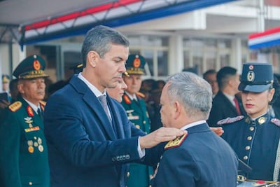 Santiago Peña en traje oscuro con corbata, coloca su mano sobre el hombro de César Silguero, vestido con uniforme militar.