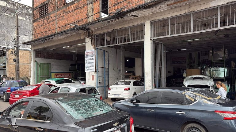 Taller automotriz lleno de vehículos dañados por granizos.