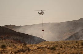 Un helicóptero de Infoca (Servicio de Extinción de Incendios Forestales de Andalucía) lanza agua mientras los bomberos continúan combatiendo un incendio forestal que causó la muerte de al menos 12 personas, cerca de Los Gallardos.