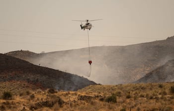 Un helicóptero de Infoca (Servicio de Extinción de Incendios Forestales de Andalucía) lanza agua mientras los bomberos continúan combatiendo un incendio forestal que causó la muerte de al menos 12 personas, cerca de Los Gallardos.