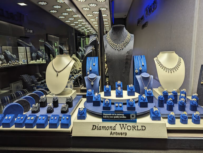 Collares y anillos de diamantes de lujo exhibidos en un escaparate iluminado de "Diamond World Antwerp". Exposición al por menor en el distrito de diamantes de Amberes, Bélgica.