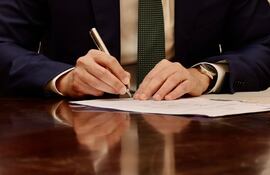 Mano de Santiago Peña con la lapicera en el momento de la firma de sus primeros decretos.