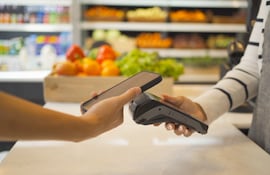 Una persona paga en un comercio con su teléfono celular sobre un pos.