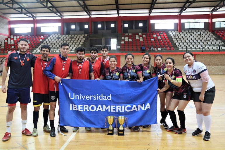 Grupo de diez personas en el gimnasio de la Universidad Iberoamericana, sosteniendo una bandera y luciendo medallas con sonrisas de felicidad.