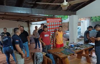 Los aprehendidos son esposados por los agentes policiales de Investigaciones de Guairá, mientras juntan las evidencias incautadas de su poder sobre una mesa.