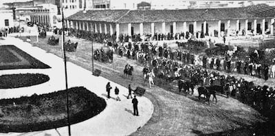 Grupo de personas escuchando un discurso en una plaza, resaltando el ambiente de conmemoración con edificios coloniales al fondo.