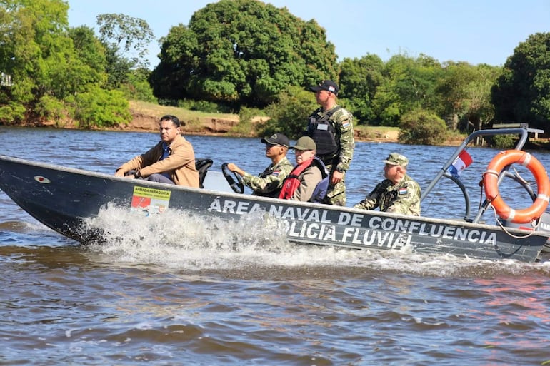 Hombres en lancha de la Armada Paraguaya, vestidos con uniformes y chalecos de seguridad, en un entorno fluvial con vegetación.