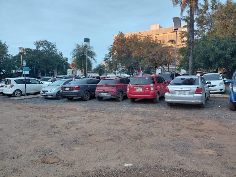 Estacionamiento vacío con varios coches de colores, entre ellos un auto rojo con bandera paraguaya.