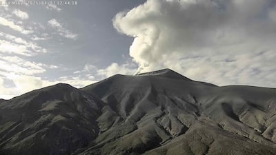 Volcán Puracé en erupción, mostrando columna de humo en un entorno natural montañoso con cielo parcialmente nublado.