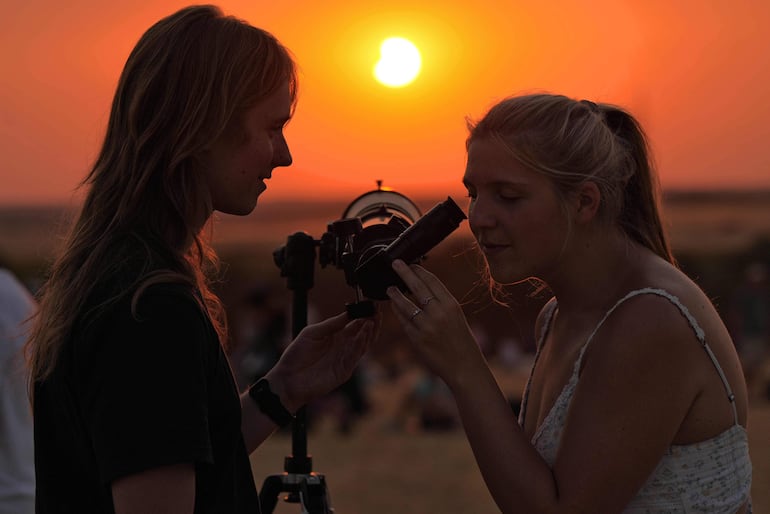 Dos mujeres observan cómo la Luna comienza a descubrir el Sol en los momentos posteriores a la totalidad del eclipse solar, en Lodoso, provincia de Burgos, el 12 de agosto de 2026.