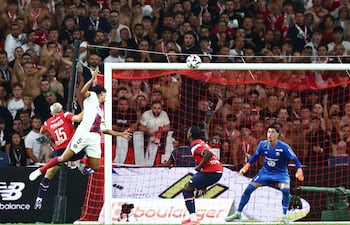 El defensa brasileño del PSG Marquinhos remata de cabeza el balón ante el guardameta turco del Lille Berke Ozer para marcar el segundo gol de su equipo durante el partido de fútbol de la L1 francesa, en el estadio Pierre-Mauroy en Villeneuve-d'Ascq, en el norte de Francia.