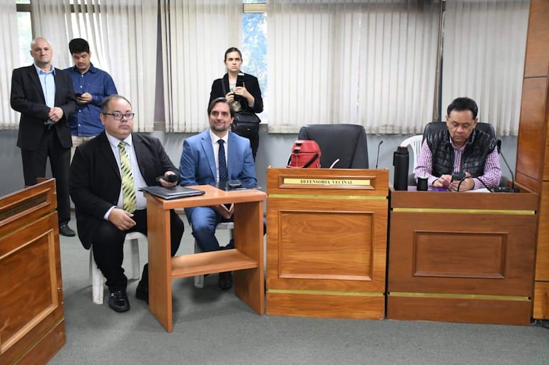 Jorge Sabaté con traje oscuro y gafas sentado, sosteniendo un micrófono, rodeado de asistentes en entorno formal.