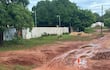 La imagen muestra un camino de tierra en mal estado, con surcos de barro y agua acumulada, que se extiende hacia el horizonte. No hay personas visibles en la escena. A la izquierda, se observa una pared de ladrillo y parte de un edificio, posiblemente habitacional, con aire acondicionado en su fachada. Al fondo, se ven palmeras que sugieren un ambiente parcialmente rural.
El suelo está cubierto de hojas y barro, lo que indica una reciente lluvia o mal drenaje en la zona. No hay identificadores de un equipo de fútbol, ni textos visibles que aporten información adicional. La escena parece reflejar problemas de infraestructura en una área residencial o rural, pero no incluye elementos noticiosos específicos. El ambiente es exterior y muestra una situación de abandono o falta de mantenimiento.