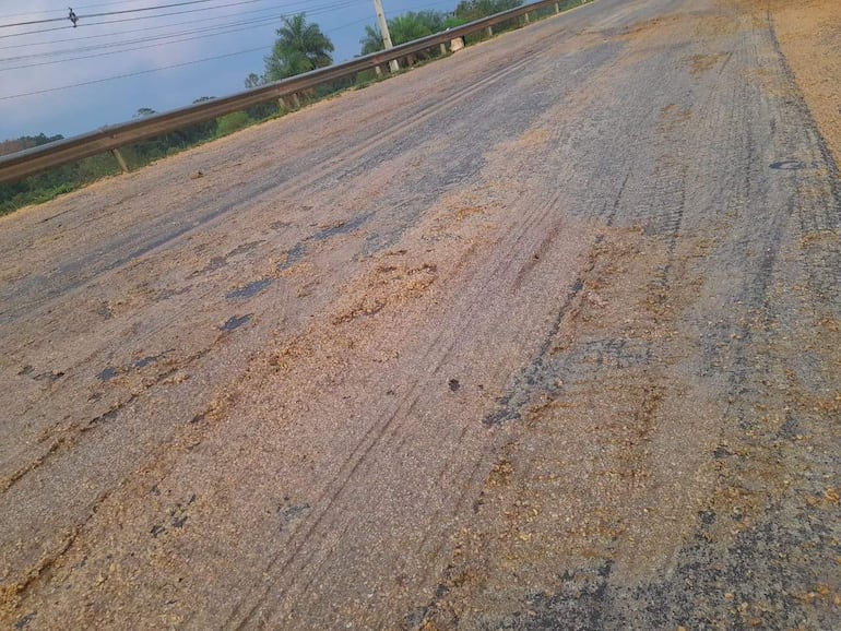 Carretera cubierta de soja tras el vuelco de un camión granelero. Vegetación al fondo sugiere clima cálido.