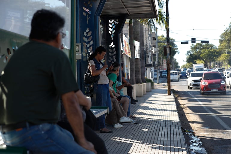 Personas esperan autobuses de servicio público en un paradero este sábado en Asunción (Paraguay). 