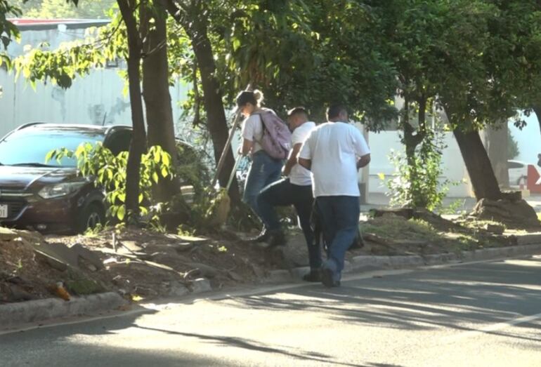 Tres funcionarios de la Municipalidad de Asunción limpiando el paseo central de la avenida Mariscal López, frente a la sede central de la comuna.