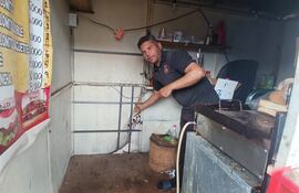 El trabajador Diego Ortiz mostrando el lugar por donde el ladrón ingresó para robar su puesto de comidas rápidas.