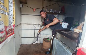 El trabajador Diego Ortiz mostrando el lugar por donde el ladrón ingresó para robar su puesto de comidas rápidas.