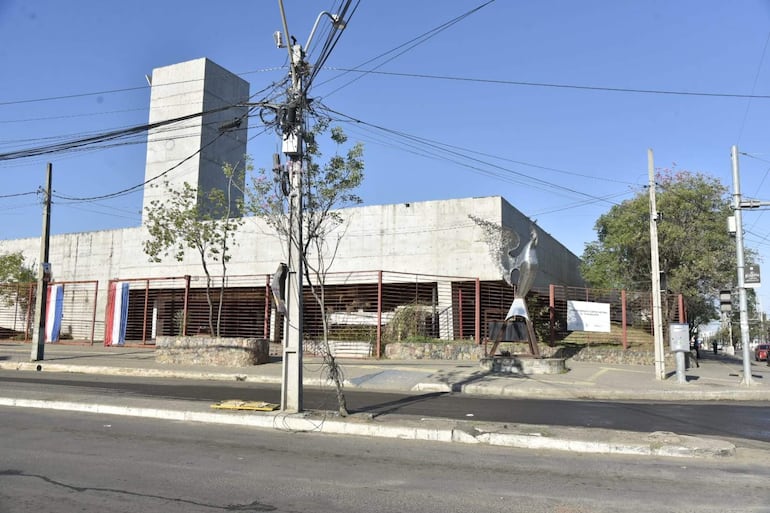 Edificio moderno en el memorial de Ycua Bolaños, decorado con banderas paraguayas y una escultura de un ave al frente.