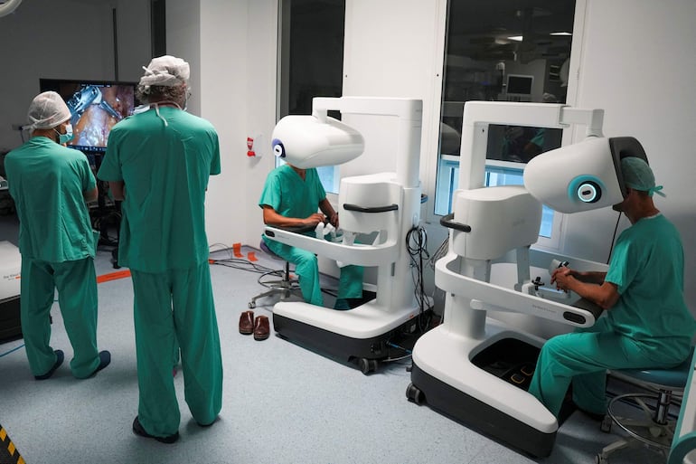 Esta fotografía, tomada el 3 de julio de 2026, muestra al cirujano Sasha Stamenkovic (derecha), director de cirugía robótica, investigación y formación, y a Ali Ansaripour (centro), médico en formación en cirugía cardiotorácica y becario en cirugía robótica, utilizando el nuevo sistema quirúrgico asistido por robot Da Vinci 5 durante una operación de cáncer de pulmón, mientras especialistas de otro centro del Servicio Nacional de Salud (NHS) observan el procedimiento en el Hospital St Bartholomew, en Londres.
