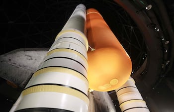 Personas caminan bajo el tanque externo de combustible y los dos propulsores de combustible sólido del transbordador espacial Endeavour de la NASA, exhibido en posición de lanzamiento en el Centro Aéreo y Espacial Samuel Oschin, durante una presentación para los medios en el Centro de Ciencias de California, en Los Ángeles, el 28 de octubre de 2026.