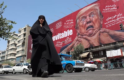 Una mujer camina junto a una valla publicitaria contra Trump en Teherán, Irán