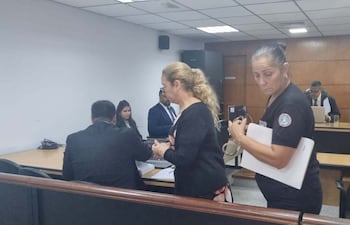 La escribana Norma Saldívar ingresaba, custodiada por una agente penitenciaria, a la sala de juicios.
