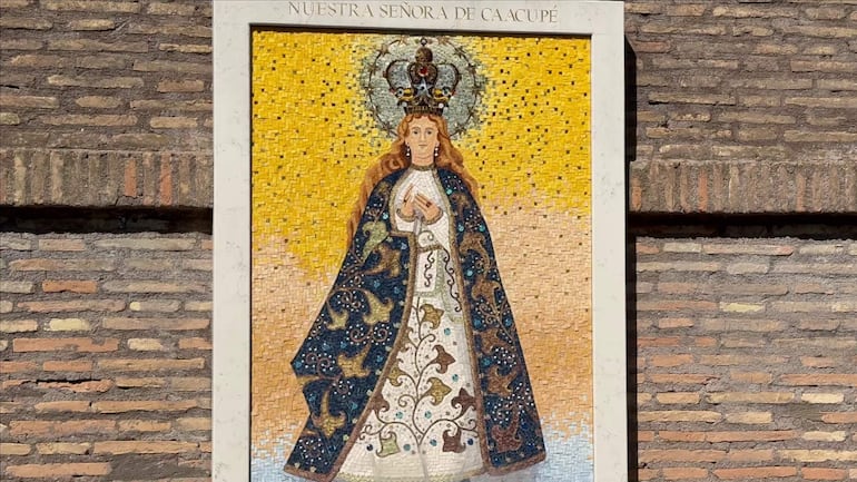 Mosaico de la Virgen de Caacupé en fondo amarillo, enmarcado en pared de ladrillos, sin personas visibles.