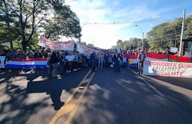 Grupo de adultos mayores en manifestación, sosteniendo pancartas y banderas en una vía pública con expresión de protesta.