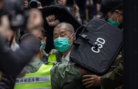 Jimmy Lai (C), director periodístico y activista prodemocracia de Hong Kong, es escoltado por la policía.
