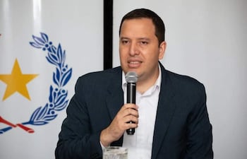 Ramírez Valdez en chaqueta oscura y camisa blanca, sostiene un micrófono con expresión seria en ambiente formal.