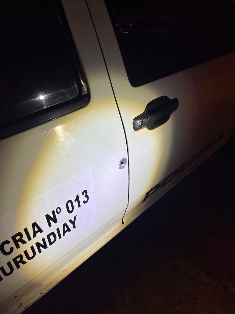 Vehículo policial blanco con daño visible en la puerta, marcado con 'POLICÍA N° 013' y 'MURUNDIAY'.
