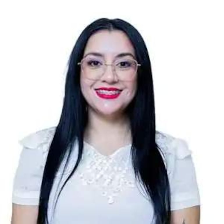 Mujer con cabello largo y negro, usando gafas y blusa blanca, sonríe frente a la cámara en un fondo blanco.