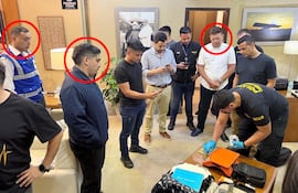 El funcionario de Dinac Gustavo Ismael Britos Orlando (chaleco azul), el pasajero Aquiles José Andrés Denis Di Lascio (campera oscura) y el pasajero Fernando Antonio Peralta Zaván (camisa blanca), tras su detención en el aeropuerto Silvio Pettirossi de Luque.