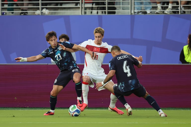 Los jugadores de Paraguay MAtías Galarza (i) y Juan José Cáceres (d) luchan por el balón con el jugador de Turquía Kenan Yildiz durante el partido del grupo D del Mundial de la FIFA 2026 entre Turquía y Paraguay, en el estadio Levi´s en Santa Clara (Estados Unidos).