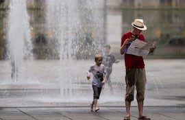 Un turista consulta un mapa de la ciudad junto a una fuente pública en la Piazza Castello durante una ola de calor en Turín.