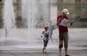 Un turista consulta un mapa de la ciudad junto a una fuente pública en la Piazza Castello durante una ola de calor en Turín.