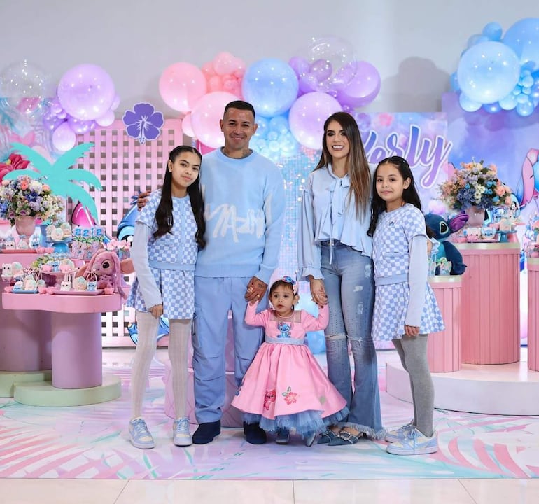 Derlis González rodeado de cuatro niñas felices, decoraciones de fiesta con globos en tonos pastel y mesas coloridas.