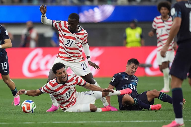 Andrés Cubas de Paraguay (der.) en acción contra Malik Tillman (izq.) y Timothy Weah (centro) de EE. UU. durante el partido de la fase de grupos de la Copa Mundial de la FIFA 2026 entre Estados Unidos y Paraguay, en Los Ángeles, California.