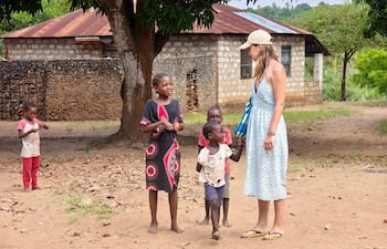 África Oriental: una turista blanca y niños africanos pobres socializan en una aldea keniata. Trabajo voluntario benéfico en países del tercer mundo.