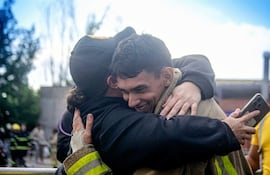 Lorena Canan en uniforme abraza a hombre de camiseta oscura, ambos sonriendo en un entorno de camaradería y alivio.